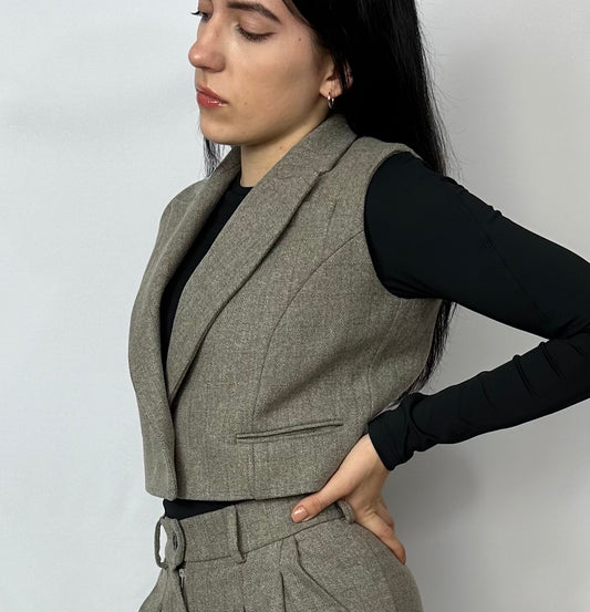 Model wearing a Sartorial Flair grey waistcoat with a single button and high-waisted trousers. The waistcoat is paired with a black long-sleeve top, showcasing a stylish and versatile smart casual look. This outfit highlights the flexibility of suits for both formal and casual occasions.