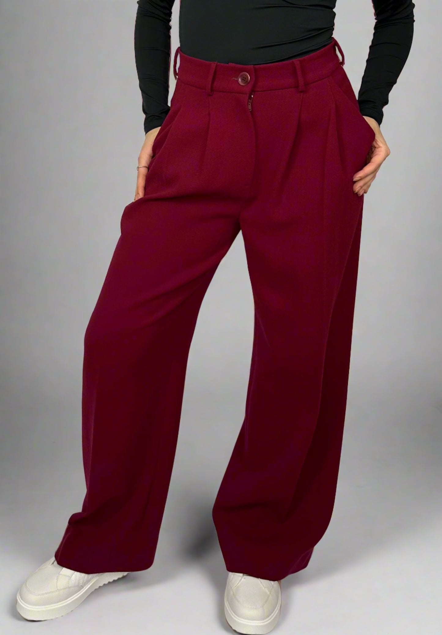 Model wearing Sartorial Flair burgundy wide-leg trousers, paired with a black top and white sneakers, showcasing a chic and elegant style.