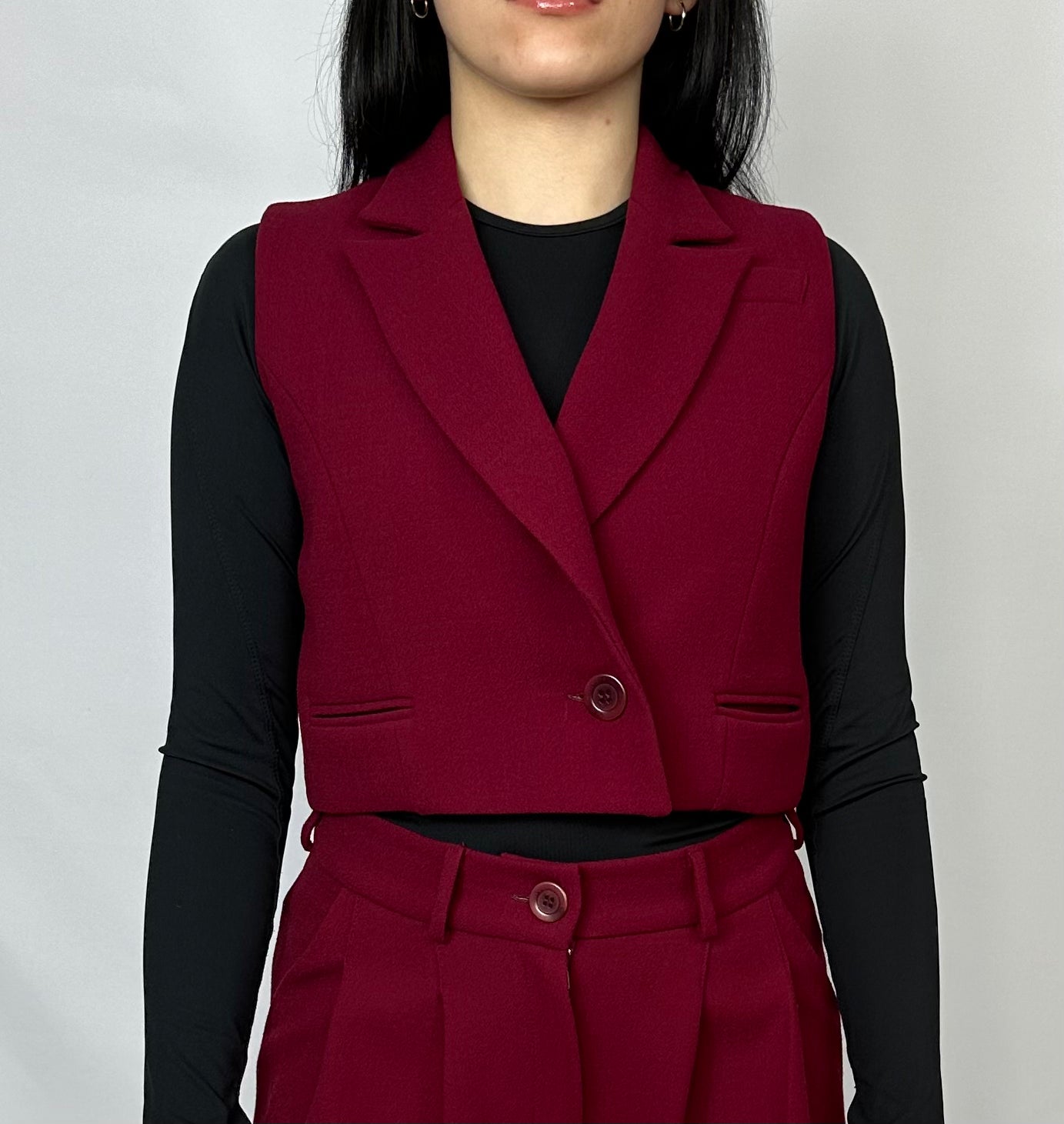 Model showcasing Sartorial Flair burgundy waistcoat and wide-leg trousers, paired with a black top, emphasizing the sleek and tailored design of the fashion-forward outfit.