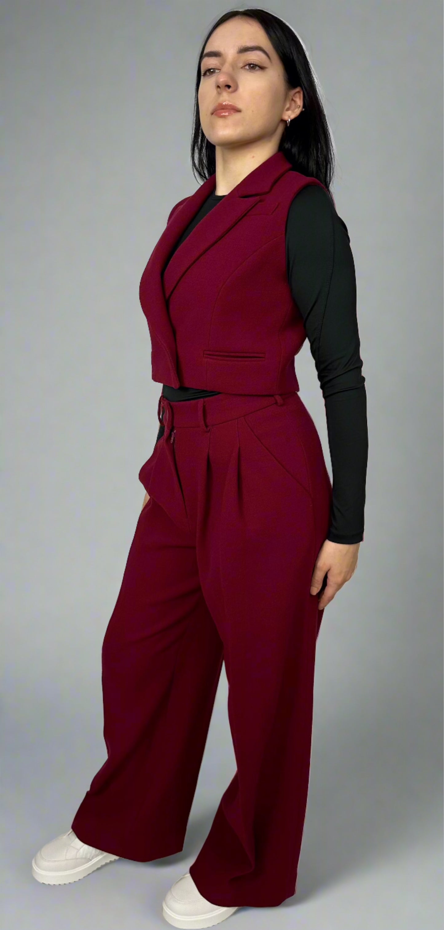 Model showcasing Sartorial Flair burgundy waistcoat and wide-leg trousers, paired with a black top and white sneakers, epitomizing modern sophistication and style.