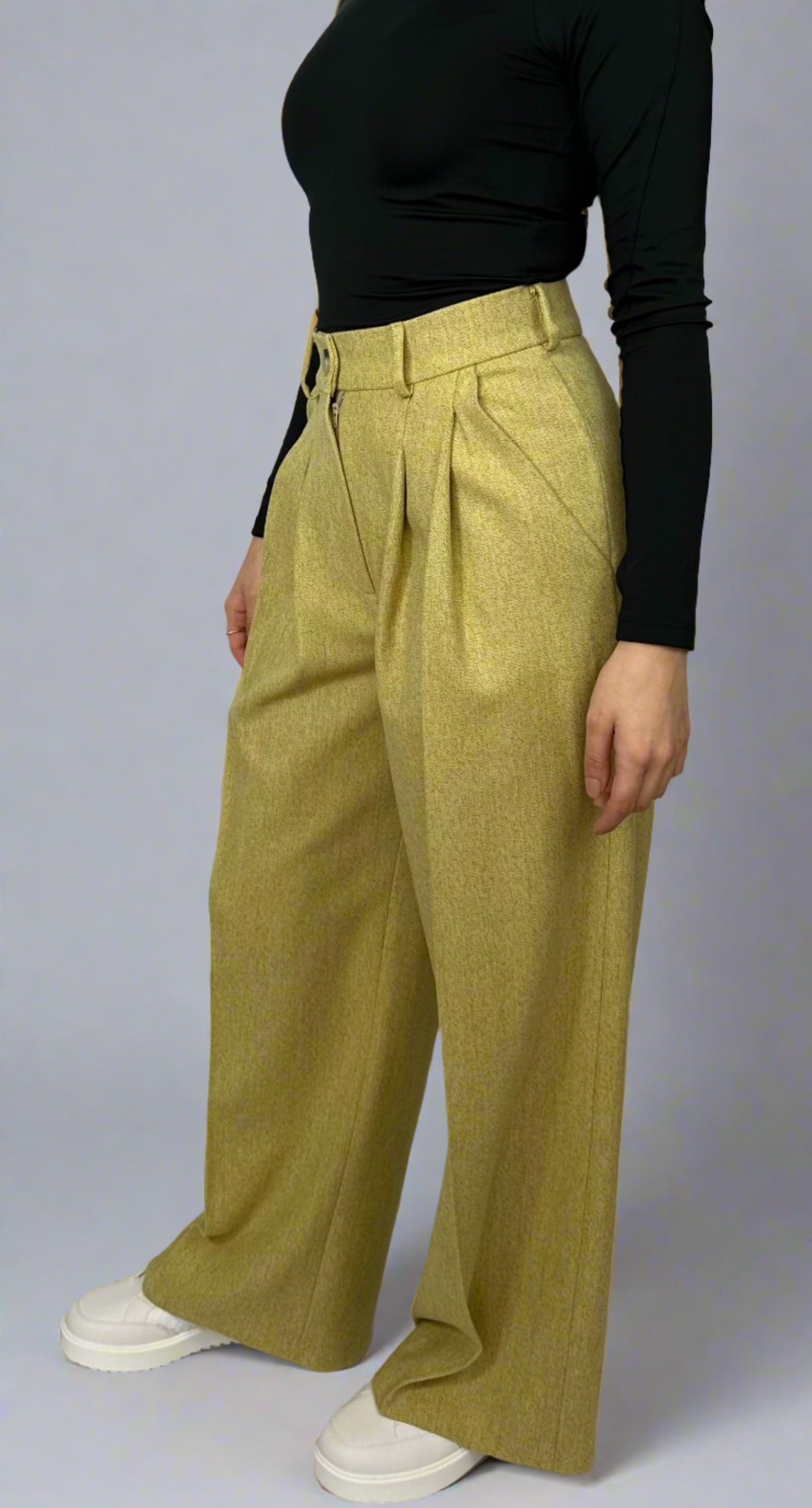 Side view of a model in Sartorial Flair’s chartreuse wool trousers featuring a high-waist design, pleated detailing, and wide-leg cut, styled with a black fitted top, showcasing modern tailoring and vibrant color for a bold fashion statement.