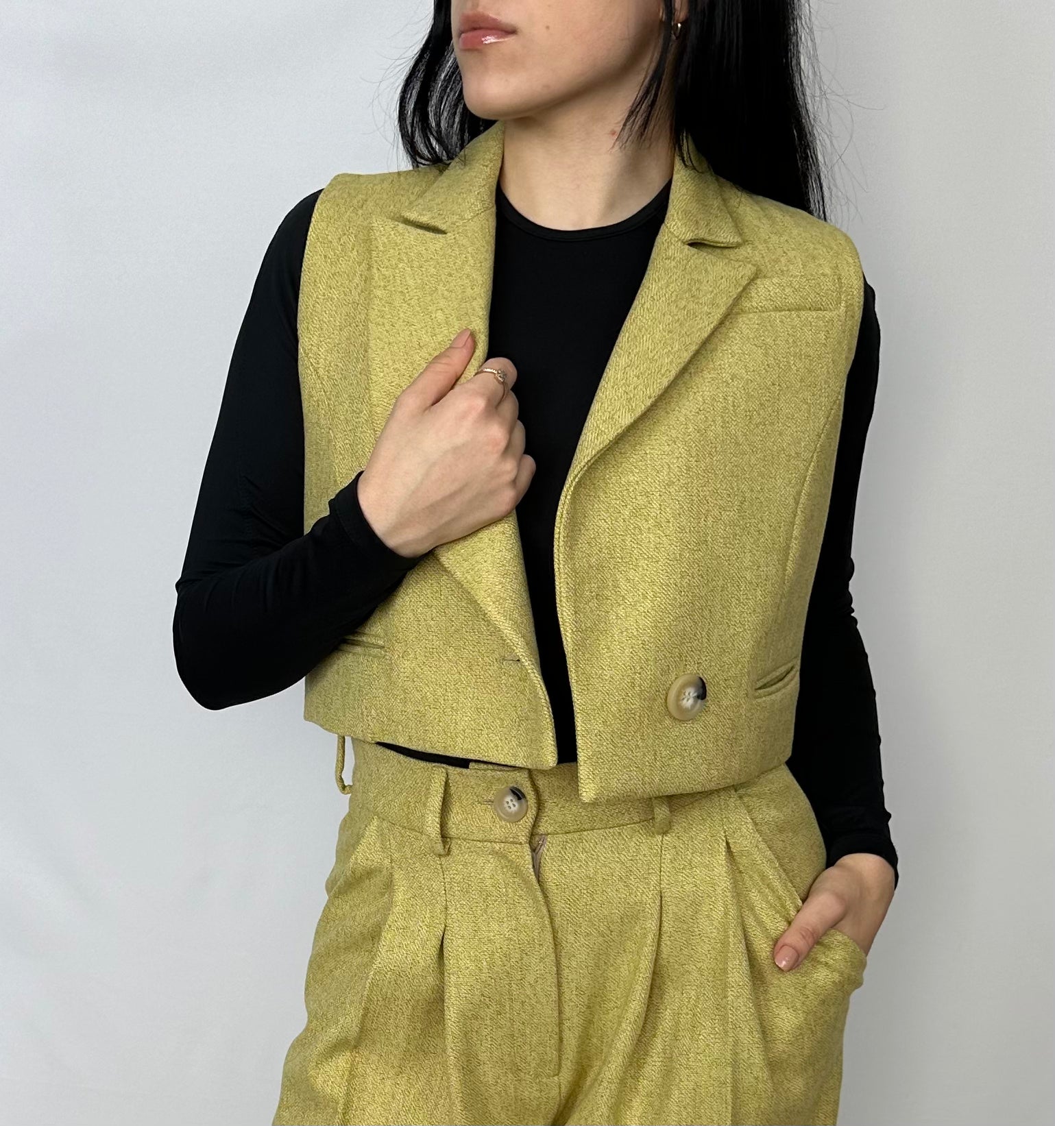 Close-up view of a woman stylishly wearing Sartorial Flair’s chartreuse wool waistcoat, featuring sharp lapels and tailored design, complemented by a black fitted top. This waistcoat is perfect for versatile, fashion-forward wardrobe choices.