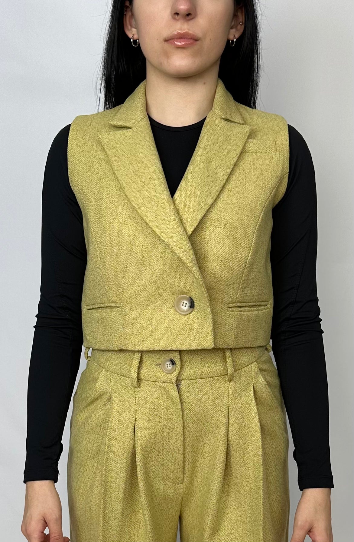 Front view of a sophisticated chartreuse wool waistcoat from Sartorial Flair, layered over a sleek black top, paired with matching high-waisted trousers. This outfit exemplifies modern elegance and versatility in women’s fashion.