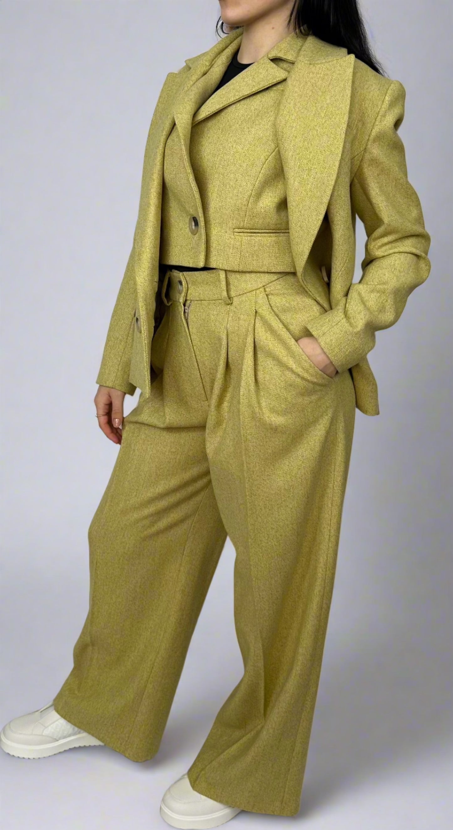 Elegant woman showcasing a three-piece Sartorial Flair suit in chartreuse, featuring a waistcoat, a textured double-breasted blazer, and wide-leg trousers, tied together with a matching belt for a sophisticated, coordinated look.