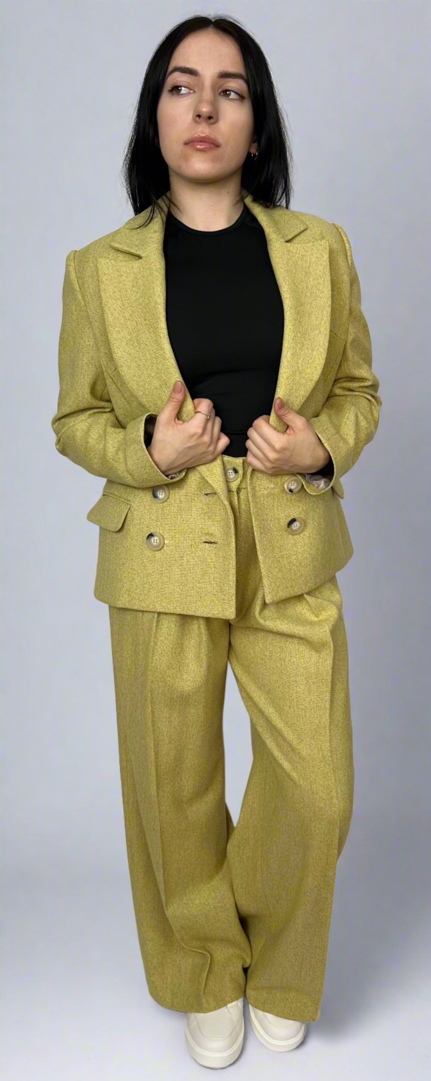 Full-length portrait of a young woman wearing a striking chartreuse Sartorial Flair suit with a double-breasted blazer and wide-leg trousers, embodying a bold and modern fashion statement.