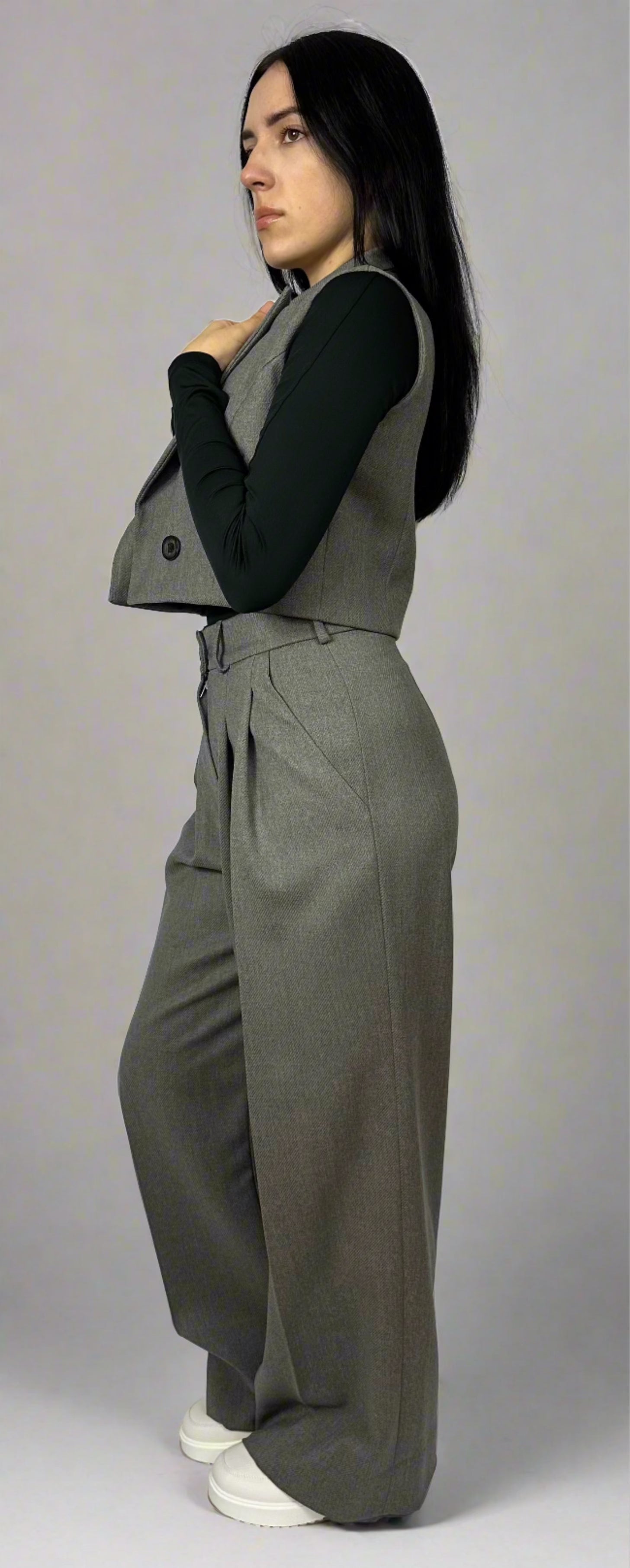 Profile view of a woman wearing a Zoe gray waistcoat over a black turtleneck, paired with tailored trousers, demonstrating a modern professional attire.