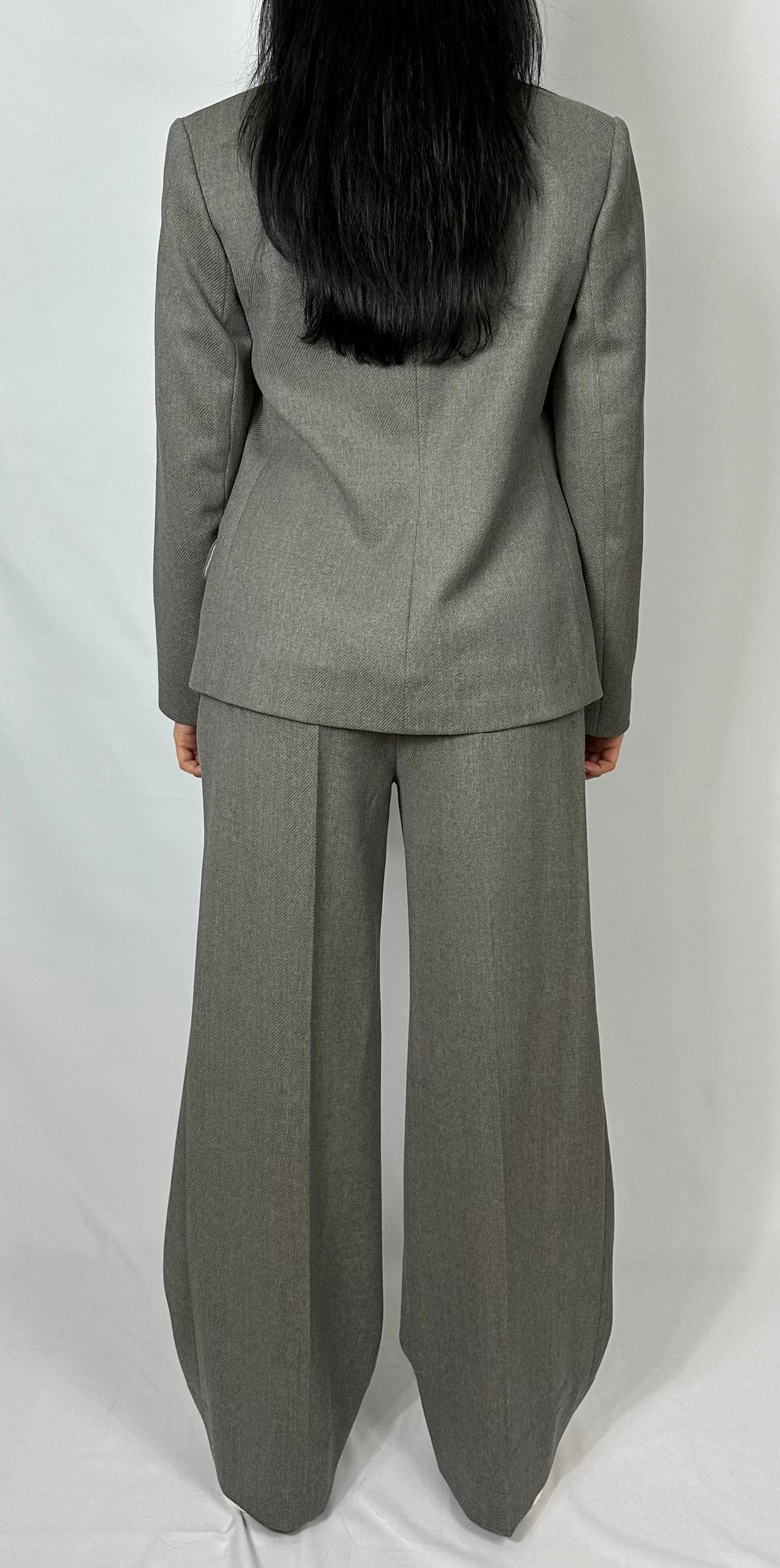 Rear view of a woman in a Zoe gray tailored suit featuring a fitted double-breasted blazer and flared trousers, perfect for professional settings, available at Sartorial Flair.