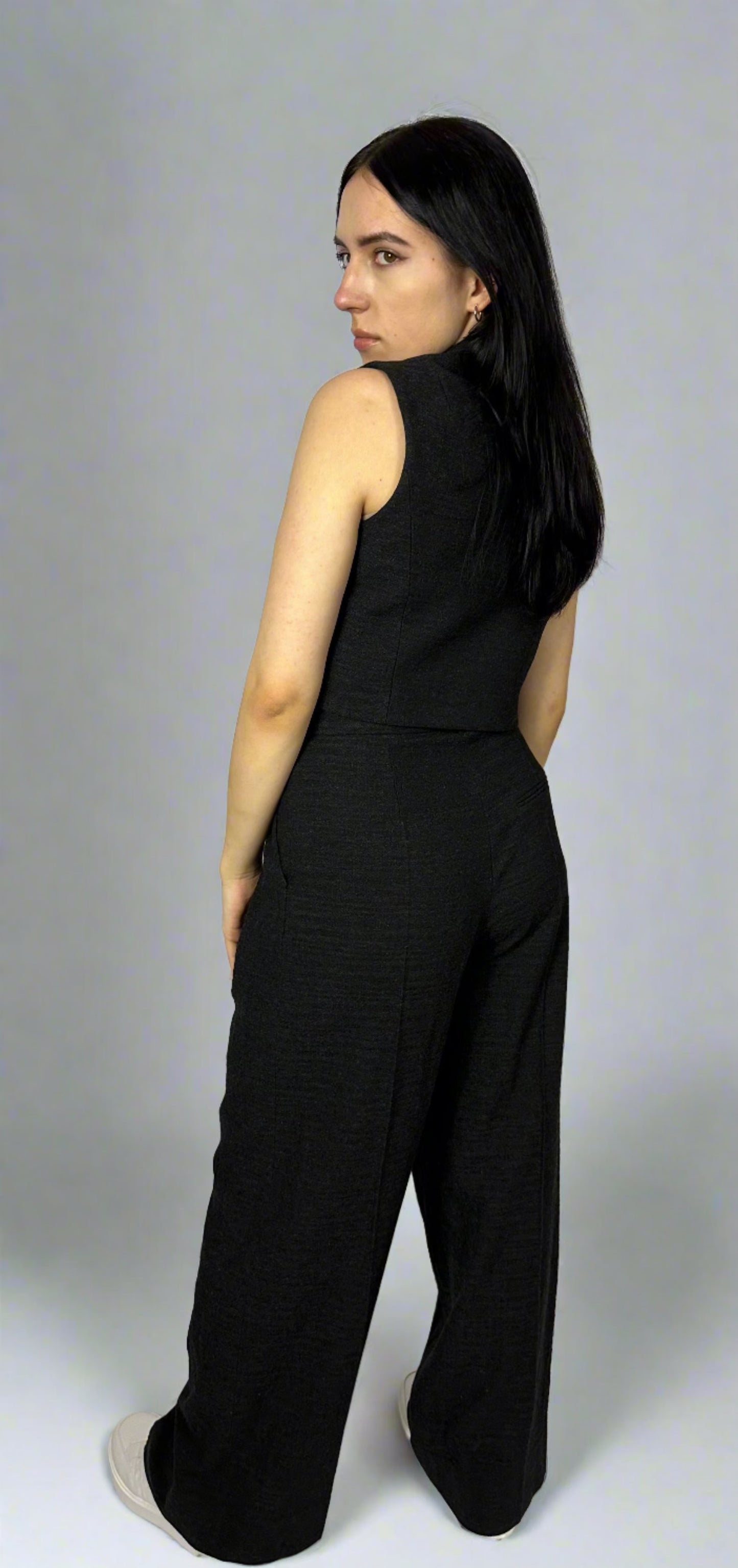 Model showcasing the back view of Sartorial Flair’s black waistcoat and wide-leg trousers, emphasizing the tailored fit, structured silhouette, and elegant drape of the high-quality fabric. Ideal for a chic, professional look.