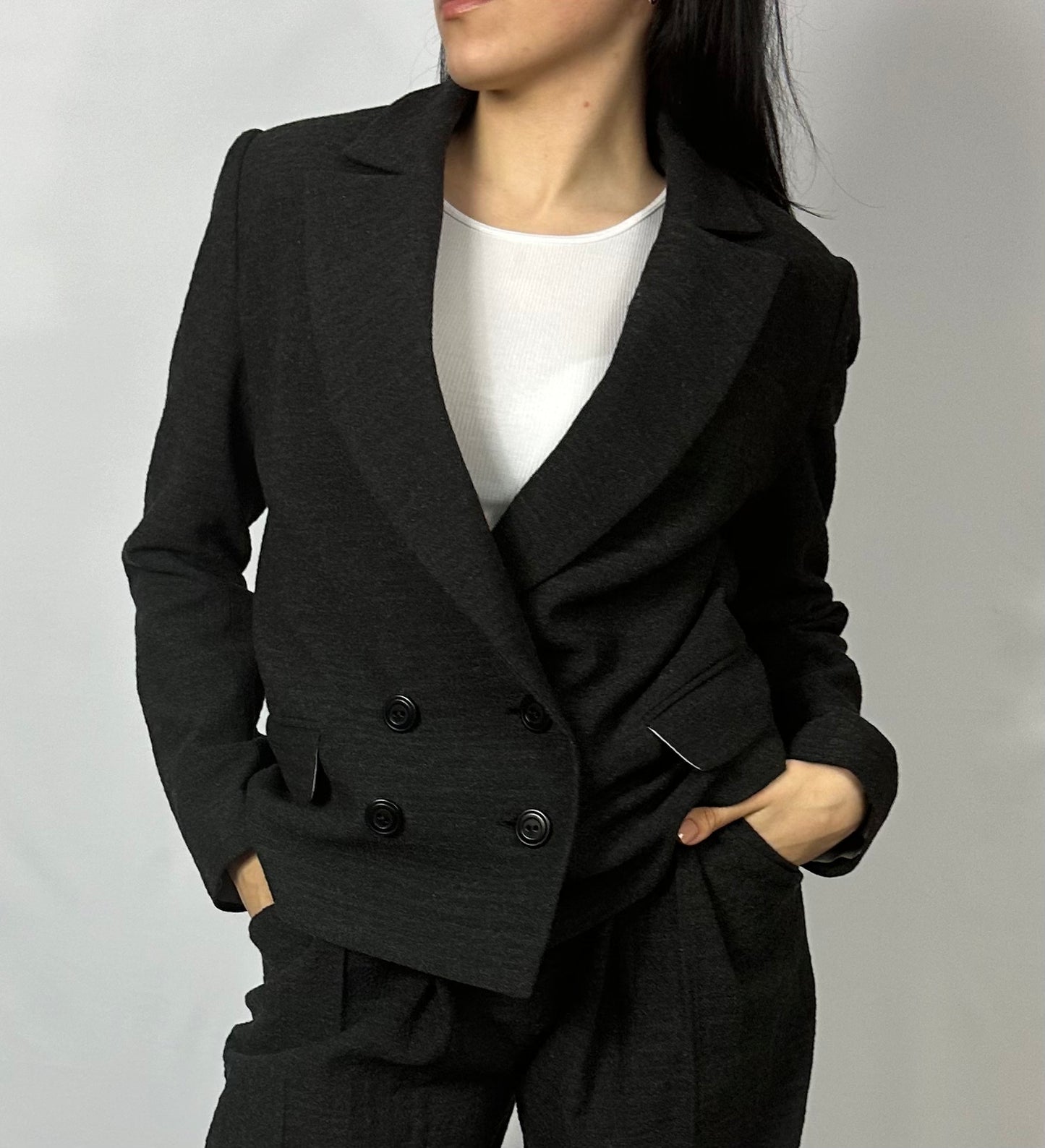 Model wearing Sartorial Flair’s black double-breasted blazer paired with matching wide-leg trousers. The tailored blazer features a classic lapel design and a double-button closure, complemented by a white inner top. This ensemble exemplifies a sophisticated and professional look, perfect for formal or business occasions, highlighting Sartorial Flair’s contemporary yet timeless fashion style.